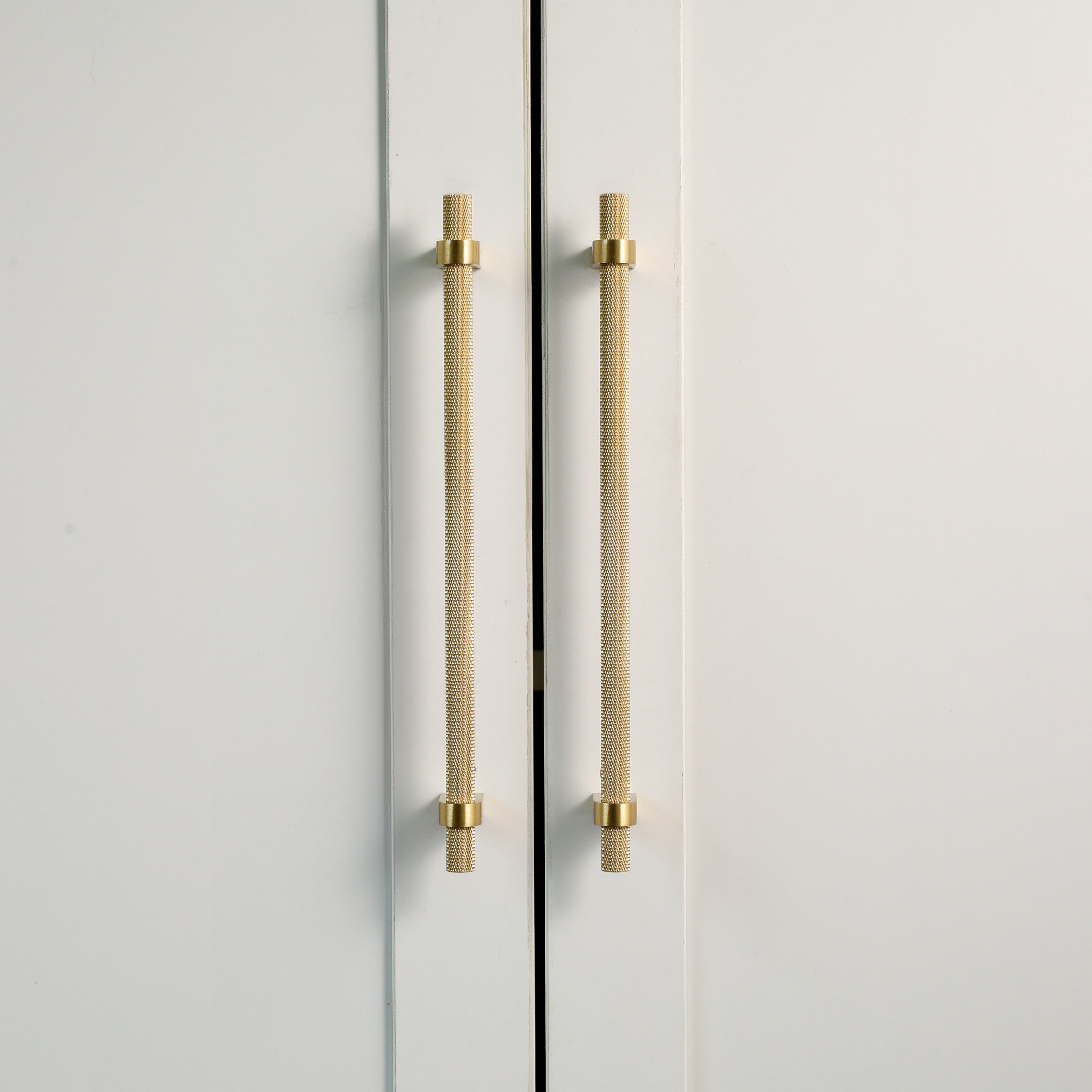 A close-up image of two cabinet doors featuring Vanderbilt Brass knurled cabinet pulls in a gold finish.